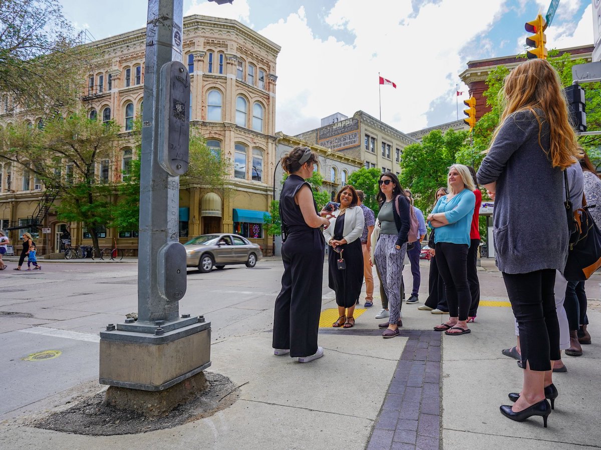 Exchange District Tours are back! - Exchange District Biz guide Laurel guiding the Tourism Winnipeg team on a tour (Maddy Reico)