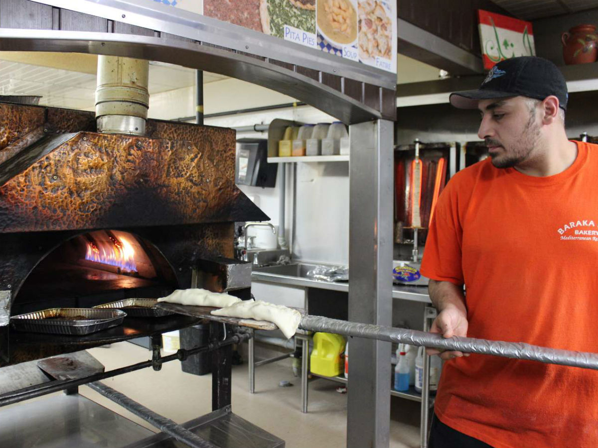 Where prominent 'Peggers Eat: Power 97's Power Mornings' Co-Host, Randy Parker  - Chef Rami Aboumrad of Baraka feeding pita pockets into the natural gas oven (PCG)