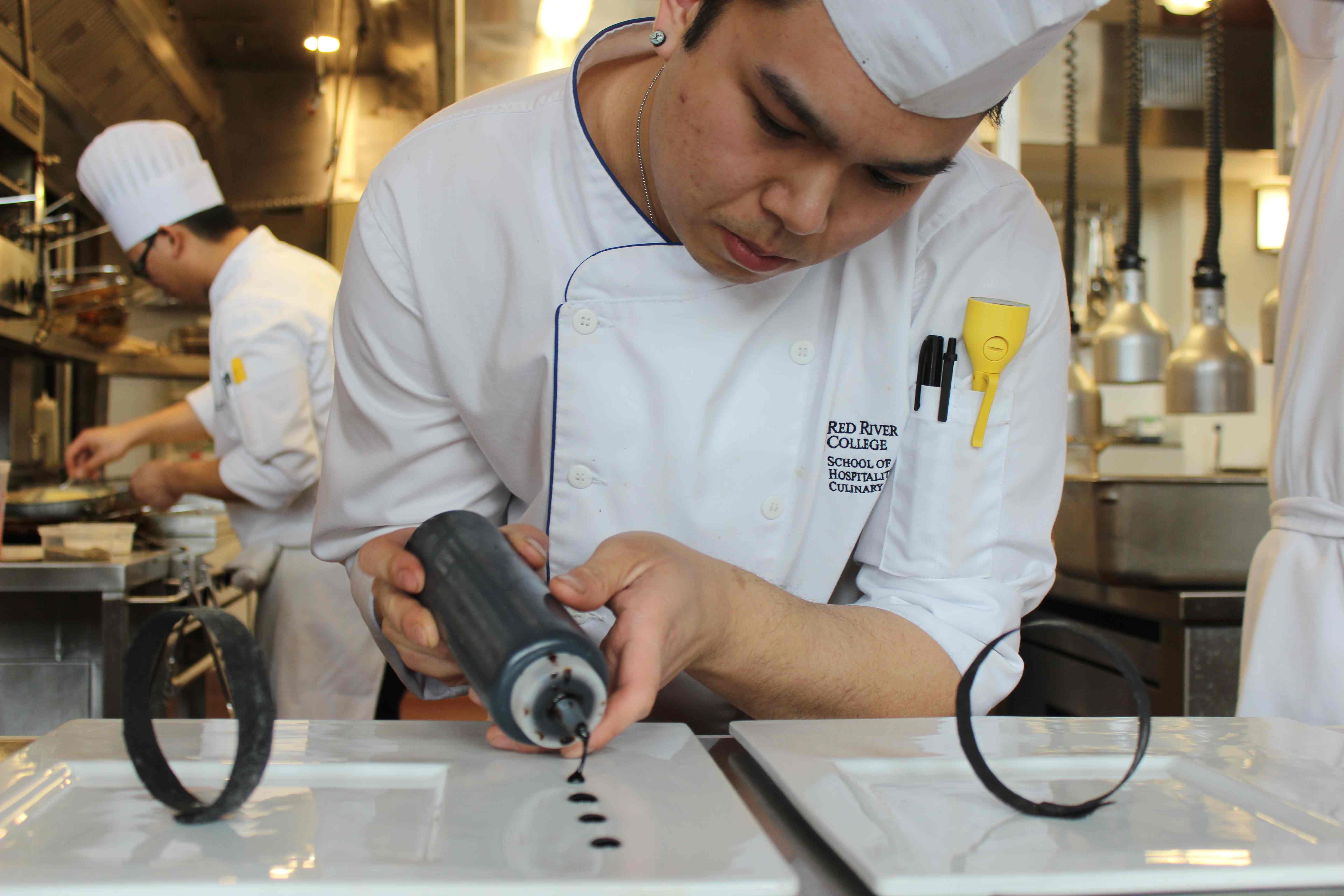 Student Alex Wong carefully dots his plates with balsamic reduction at Jane's. (photo by robin summerfield.)