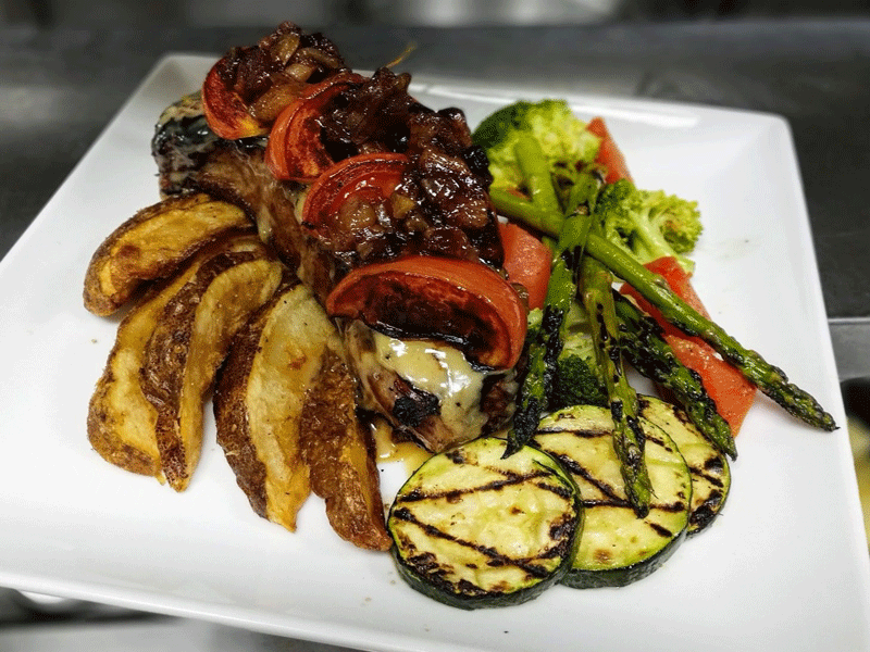 Rae's Bistro & Lounge - 12oz. NY Striploin grilled the way you like it and smothered in creamy honey dijon sauce, topeed with grilled heirloom tomato and coffee bacon jam, served along crops potato wedges and local Manitoba vegetables.