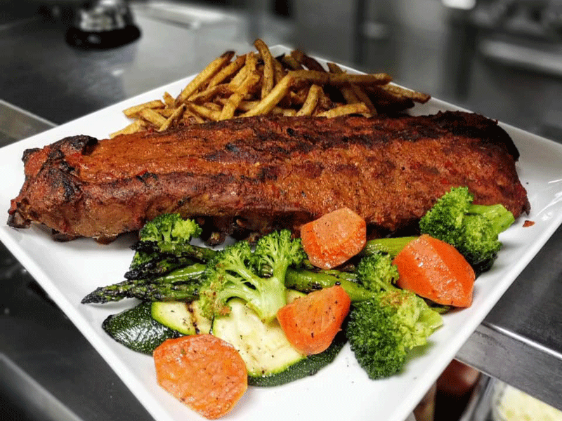 Rae's Bistro & Lounge - 30oz. rack of Manitoba back ribs braised and smoked in house, slathered in spicy Caribbean jerk sauce made with crimson hot peppers.